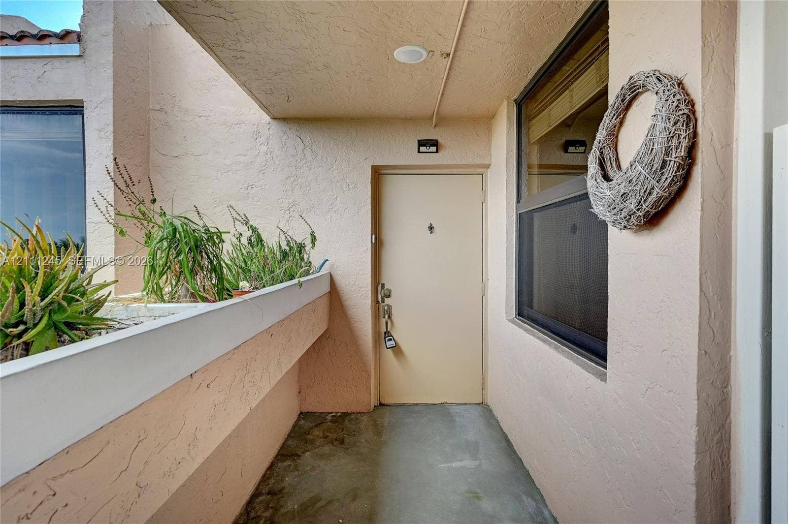 6800 Cypress Road, #506, Plantation, FL 33317 Covered entryway featuring textured stucco walls, a concrete floor, integrated recessed lighting, and a built-in stucco planter