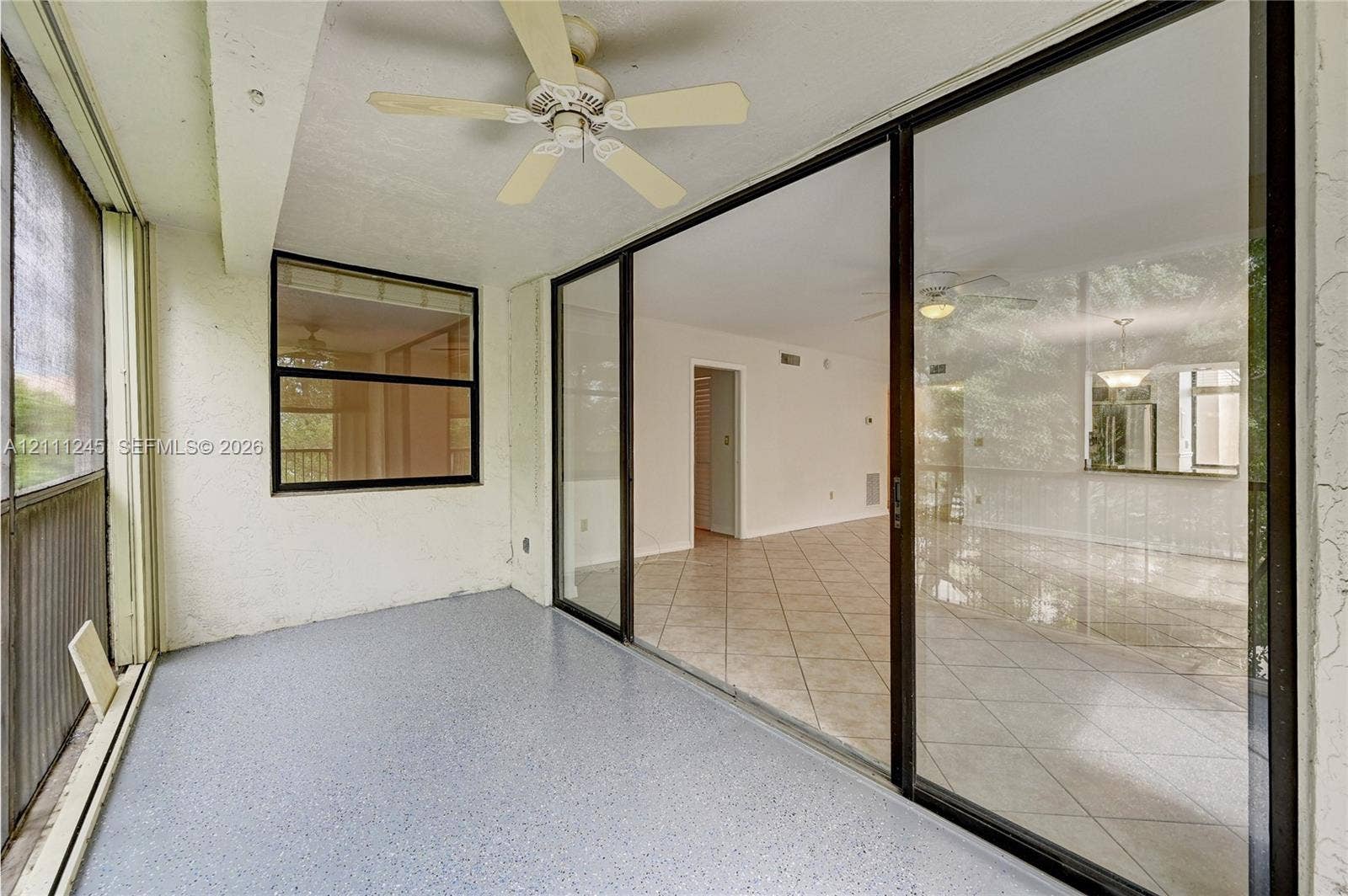 6800 Cypress Road, #506, Plantation, FL 33317 Screened-in porch featuring expansive glass sliding doors, painted concrete flooring, and a ceiling-mounted fan