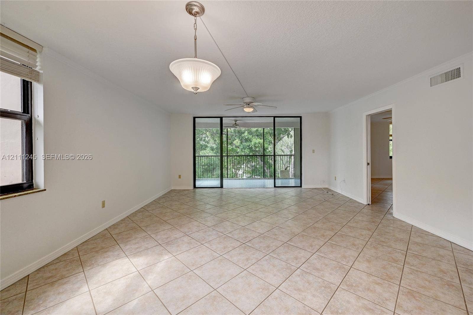 6800 Cypress Road, #506, Plantation, FL 33317 Open-concept interior featuring large-format diagonal tile flooring, a dual-light hanging pendant fixture, a ceiling fan with integrated lighting, and floor-to-ceiling sliding glass doors opening to a screened balcony