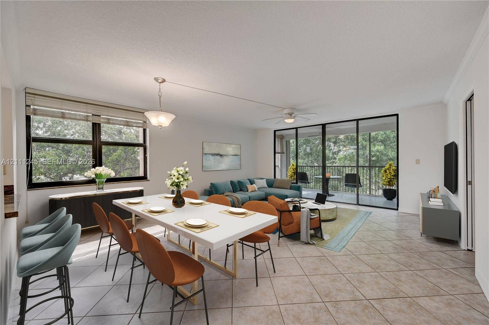 6800 Cypress Road, #506, Plantation, FL 33317 Open-concept living space featuring diagonal-set tile flooring, multi-panel sliding glass doors to the balcony, recessed crown molding, and a ceiling fan with integrated lighting