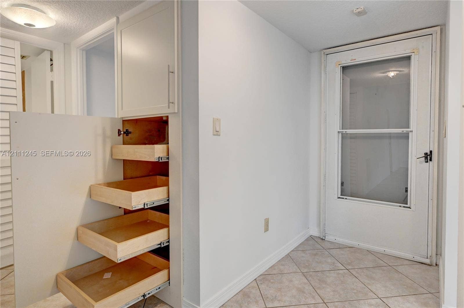 6800 Cypress Road, #506, Plantation, FL 33317 Built-in floor-to-ceiling cabinetry featuring pull-out wooden drawers, ceramic tile flooring, and a glass-paneled exterior door