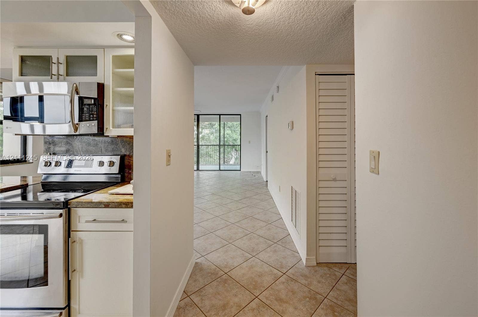 6800 Cypress Road, #506, Plantation, FL 33317 Kitchen featuring stainless steel appliances, white cabinetry, stone-finish countertops, and tile flooring