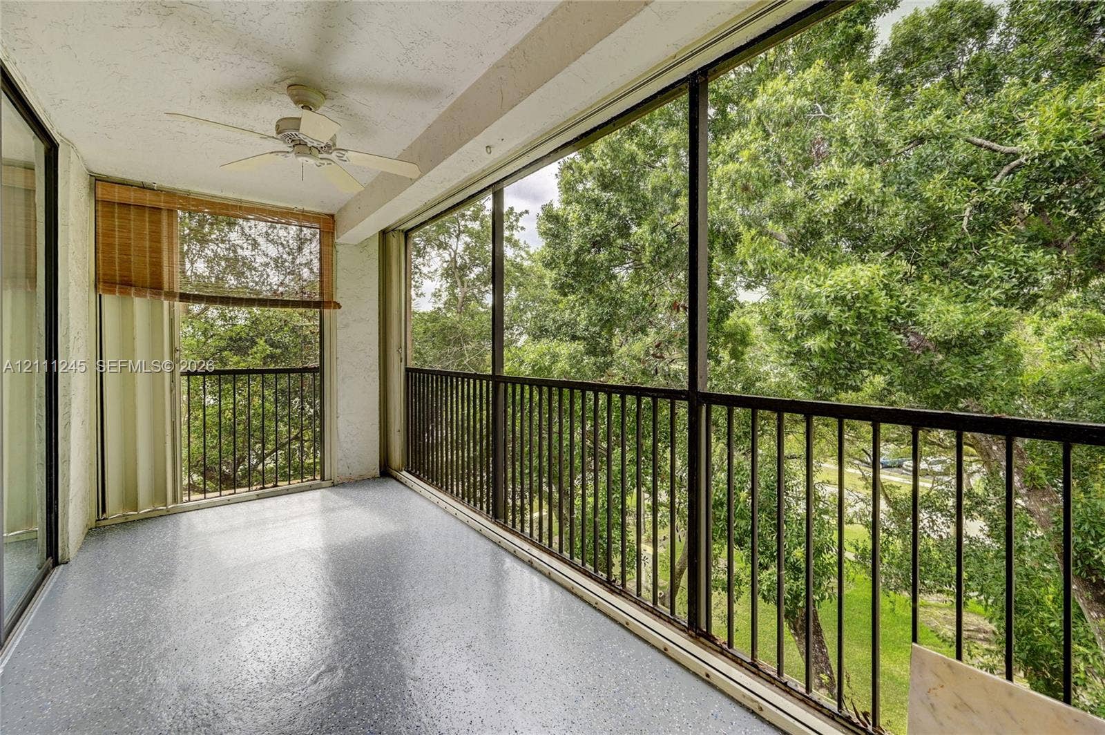 6800 Cypress Road, #506, Plantation, FL 33317 Screened balcony featuring black metal railings, textured concrete flooring, and a ceiling-mounted fan