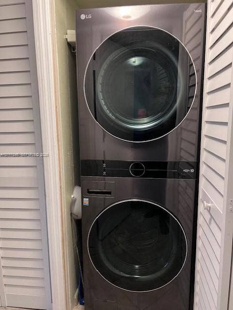 6800 Cypress Road, #506, Plantation, FL 33317 Stackable laundry unit featuring a sleek black finish, glass-front doors, and louvered closet doors