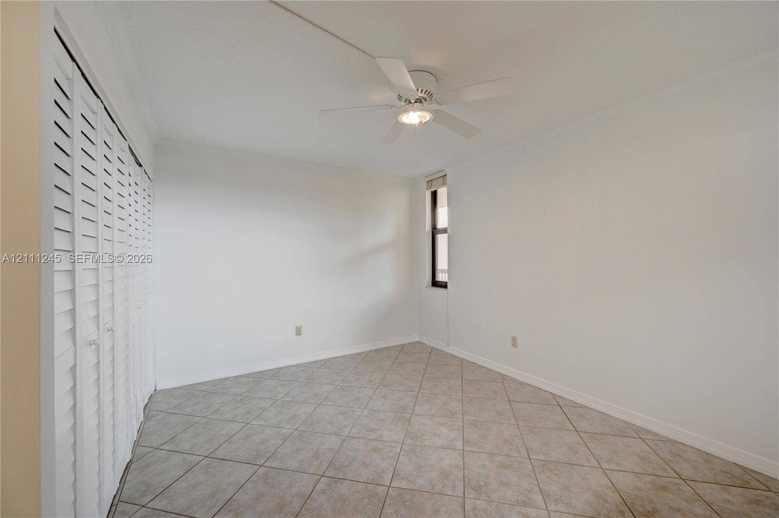 6800 Cypress Road, #506, Plantation, FL 33317 Interior space featuring diagonal tile flooring, white louvered closet doors, and a ceiling fan with integrated lighting