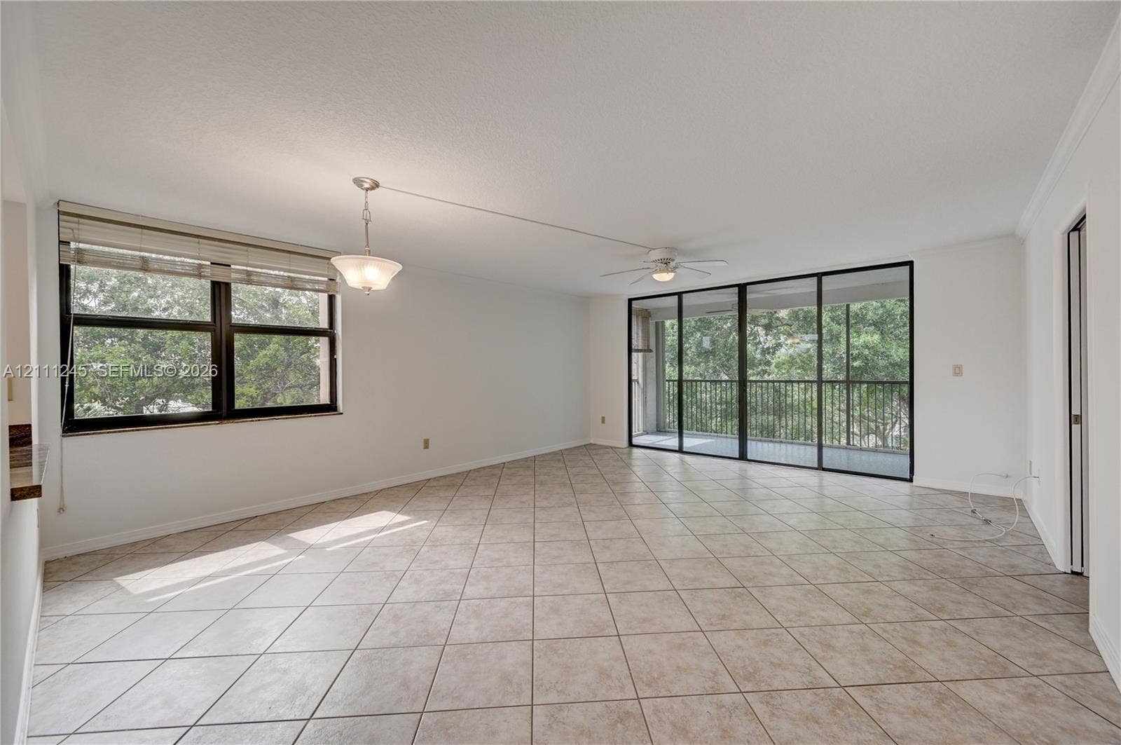 6800 Cypress Road, #506, Plantation, FL 33317 Neutral ceramic tile flooring, floor-to-ceiling sliding glass doors, integrated ceiling fan, and pendant lighting
