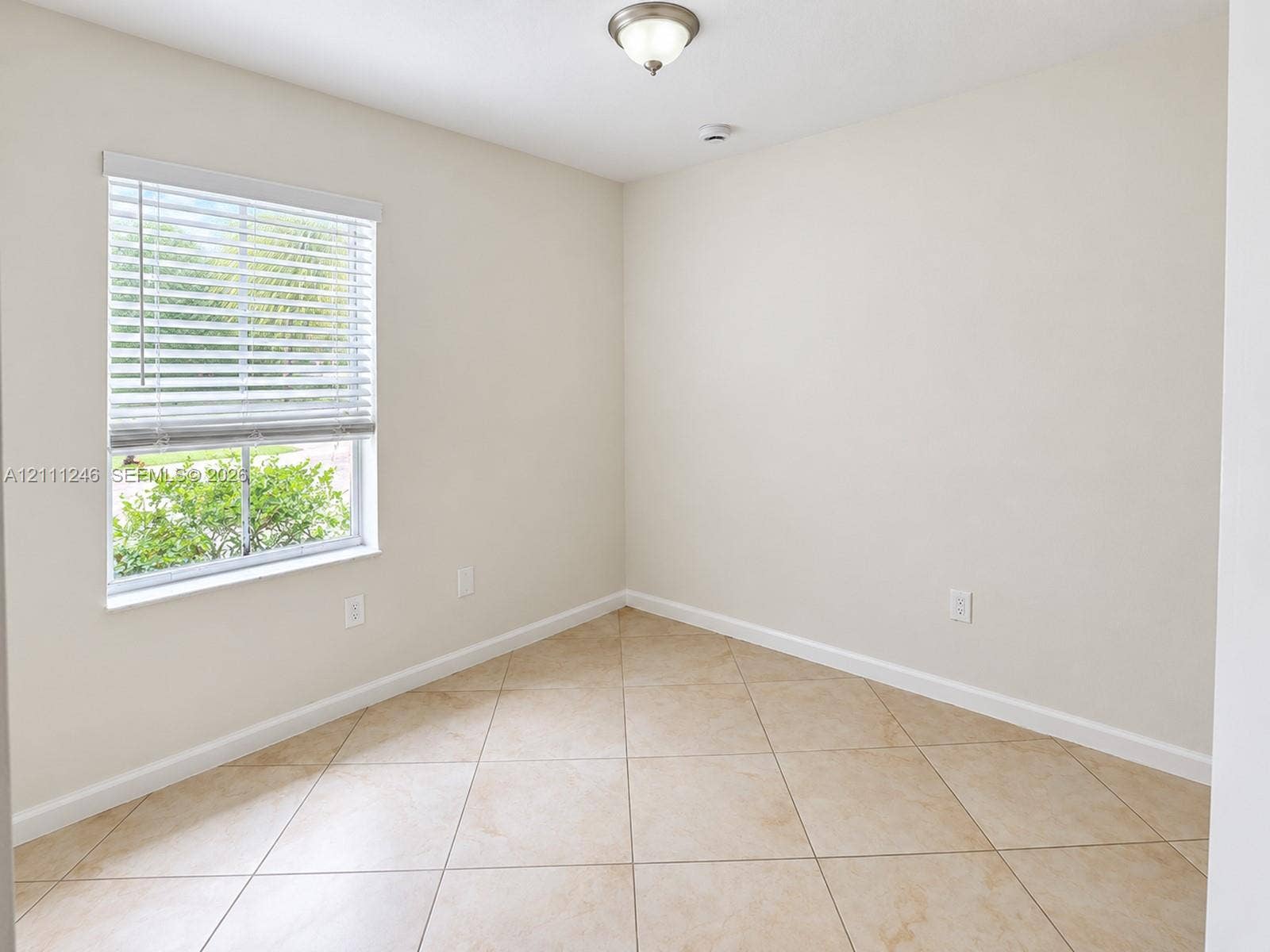 Neutral wall tones, diagonal-laid tile flooring, and a single-hung window with white horizontal blinds