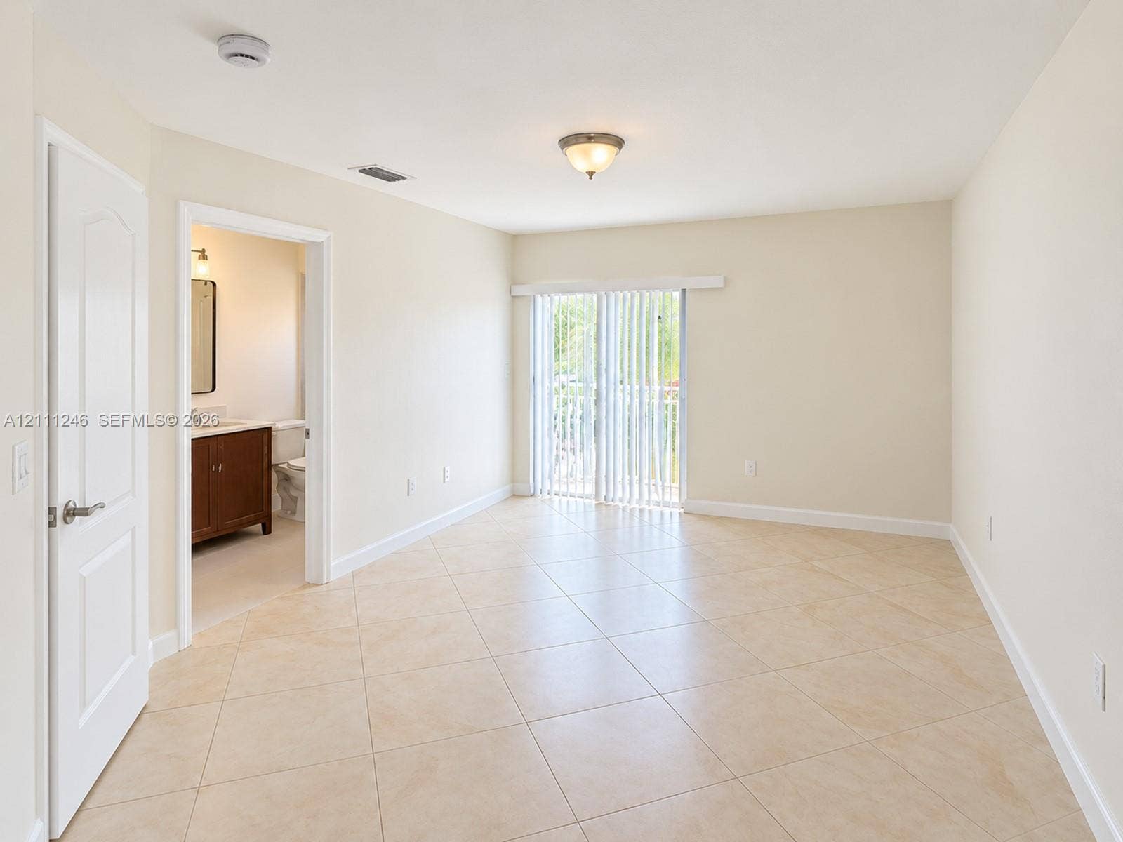 Neutral-toned tile flooring, sliding glass doors with vertical blinds, and a built-in flush-mount light fixture