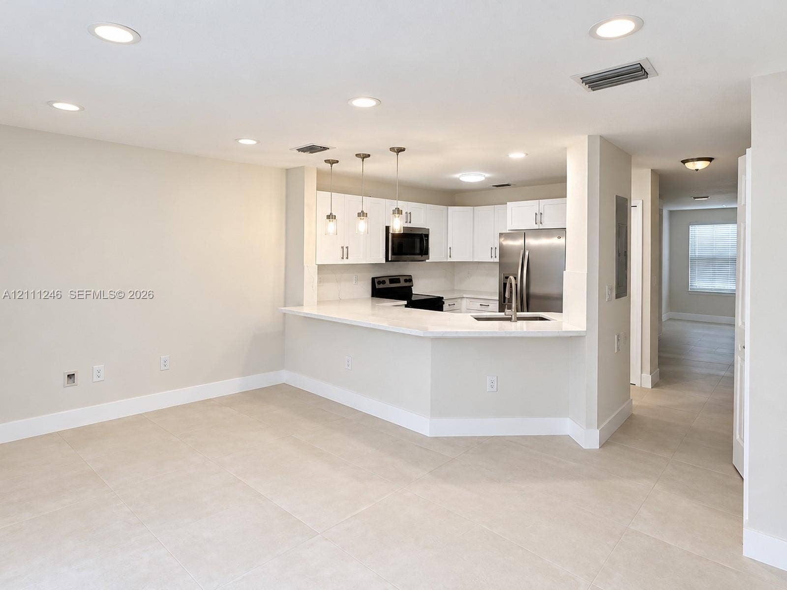 Kitchen featuring white cabinetry, solid-surface countertops, stainless steel appliances, a breakfast bar, and recessed lighting