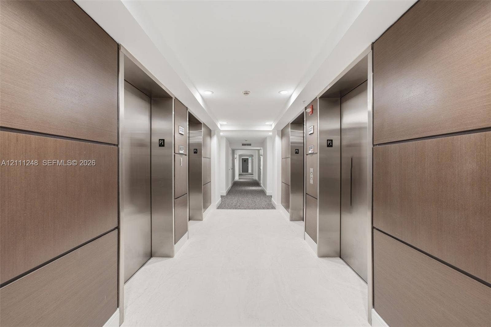 Elevator lobby featuring metallic doors, wood-paneled walls, and recessed ceiling lighting