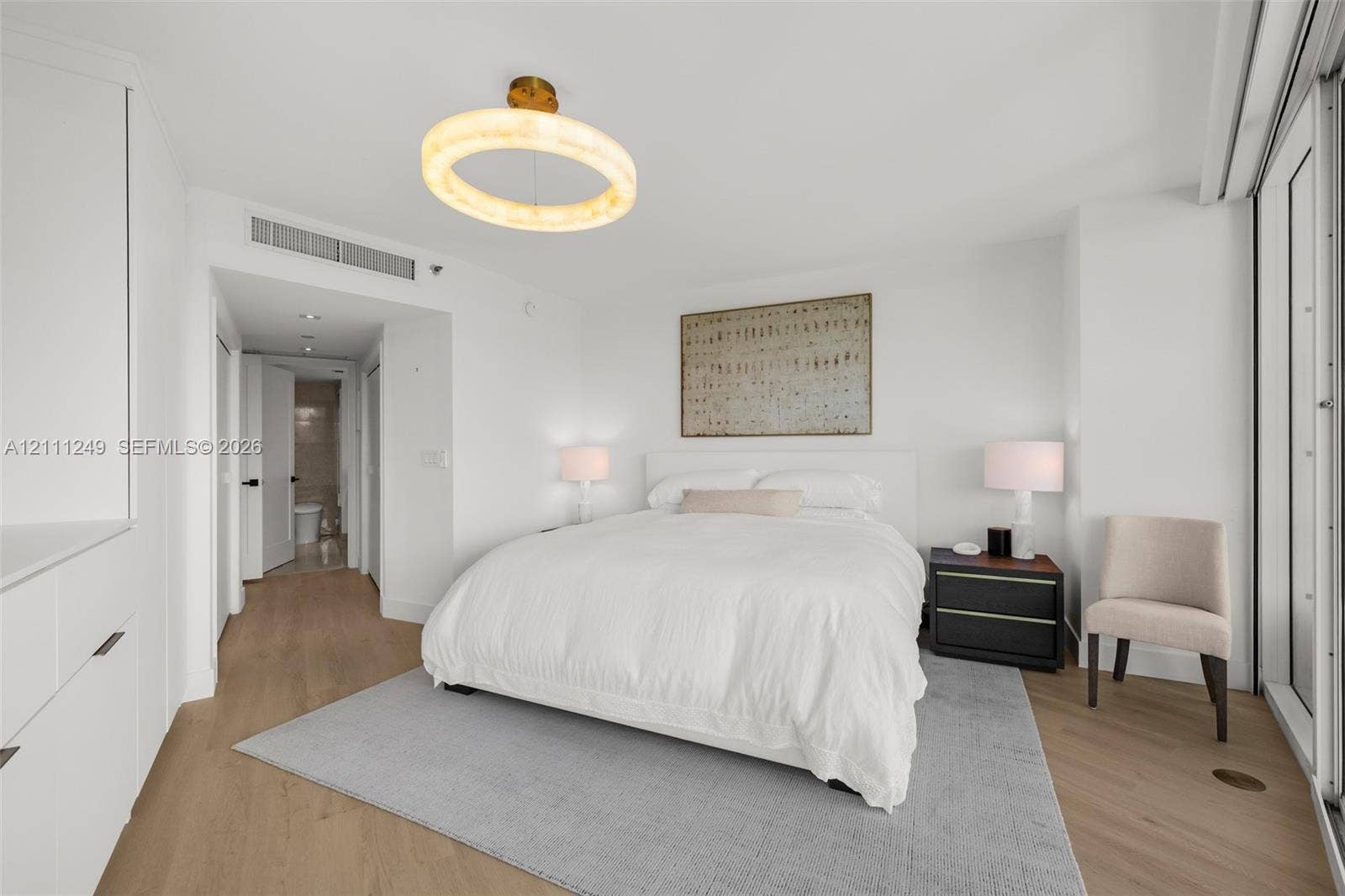 Wood-finish flooring, custom built-in cabinetry, and a circular geometric chandelier