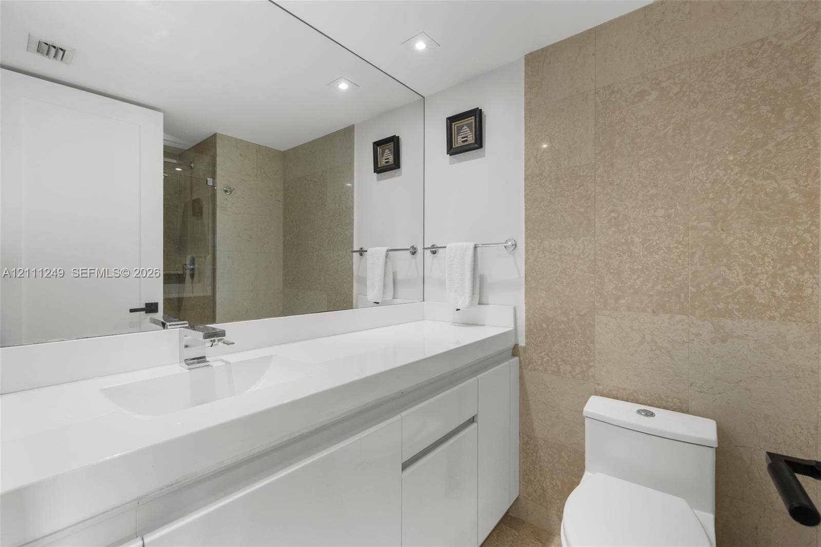 Walk-in shower featuring a glass enclosure, rainfall showerhead, wall-mounted control valve, and stone-finish wall tile
