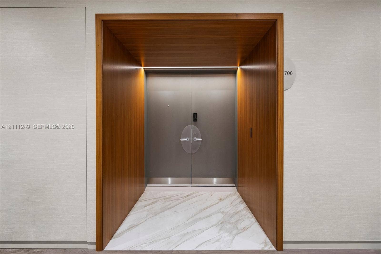 Stone tile flooring featuring geometric inlay, recessed lighting, and a white interior door with matte black hardware