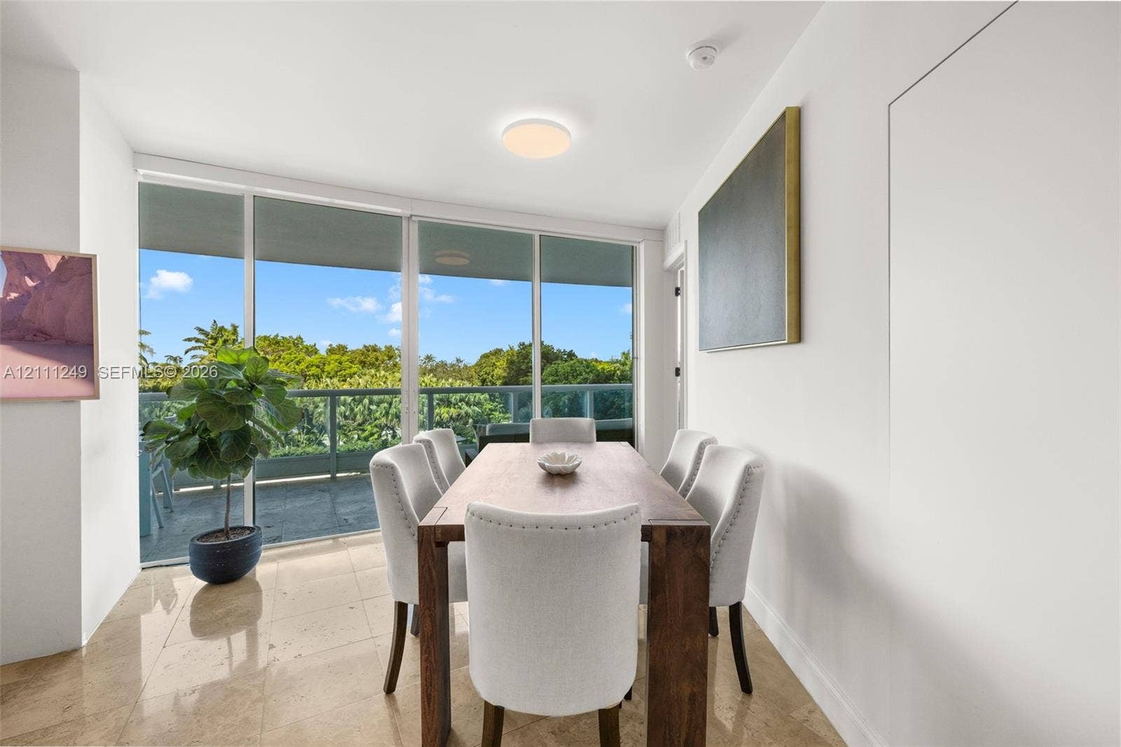 Floor-to-ceiling glass panel windows, polished stone flooring, and access to a balcony with metal railing