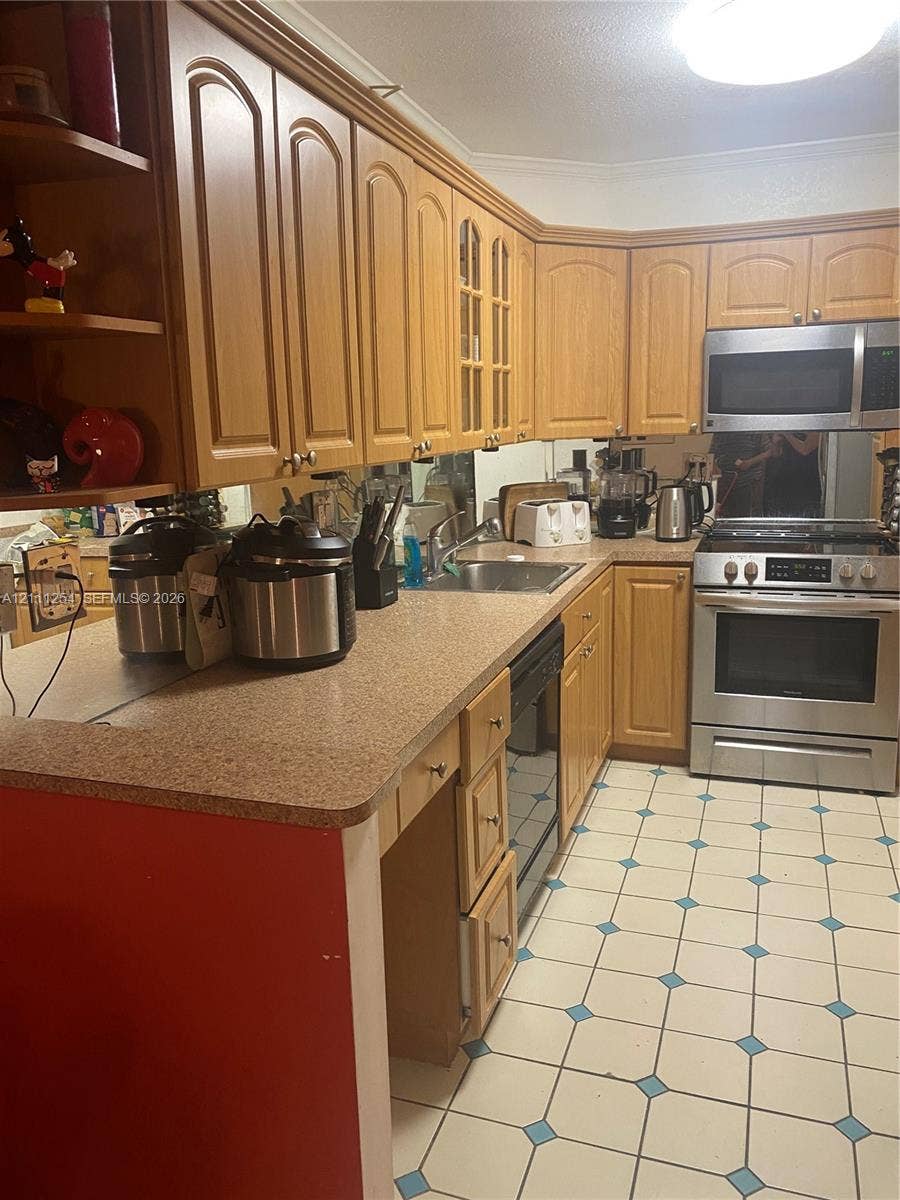 300 Bayview Drive, #409, Sunny Isles Beach, Sunny Isles Beach, FL 33160 Kitchen featuring light-tone wood cabinetry, stone-composite countertops, stainless steel appliances, and tile flooring with decorative inlay accents