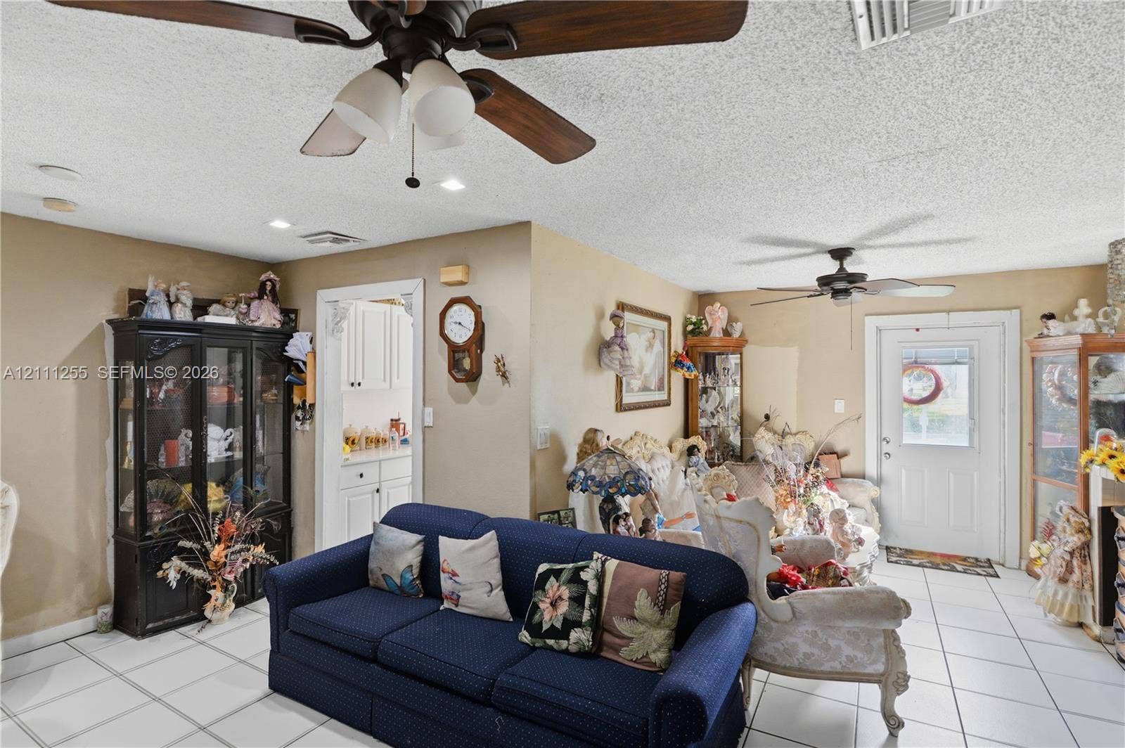 Neutral-toned interior featuring large-format ceramic tile flooring, two ceiling-mounted fans with light kits, and recessed lighting