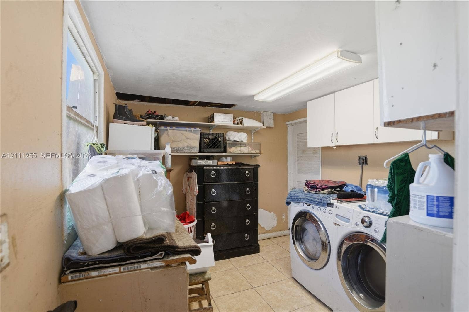 Utility space featuring ceramic tile flooring, wall-mounted cabinetry, and dual built-in metal shelving units
