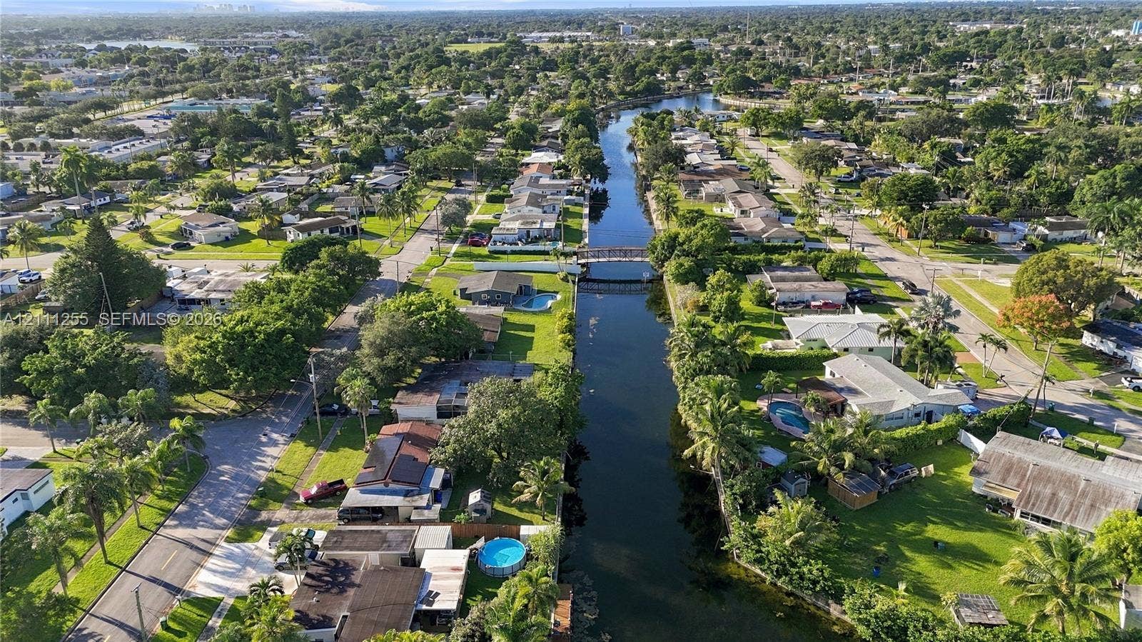Aerial perspective of a canal-front property featuring mature vegetation and established residential landscaping