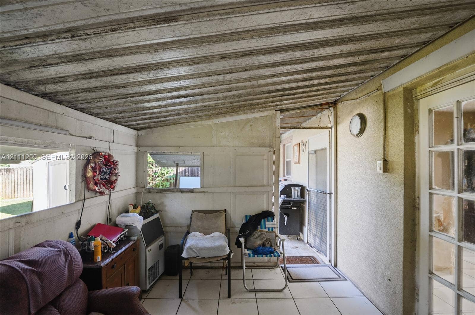 Covered patio featuring corrugated metal ceiling, ceramic tile flooring, and multi-pane glass entry door