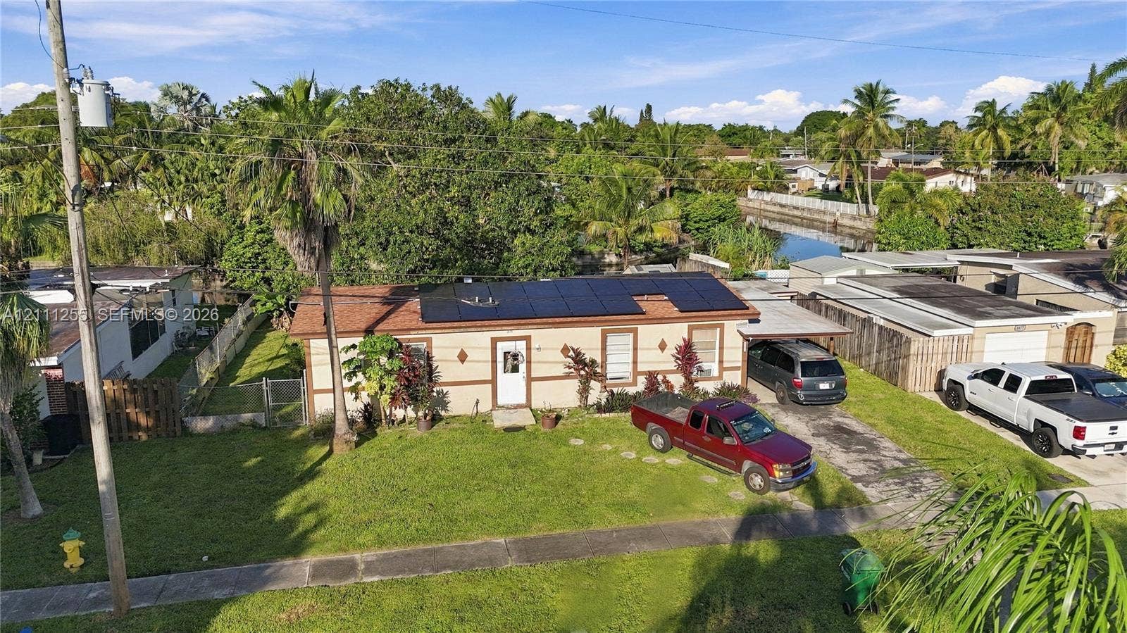 Single-story residence featuring rooftop solar panels, a covered carport, and a manicured front lawn