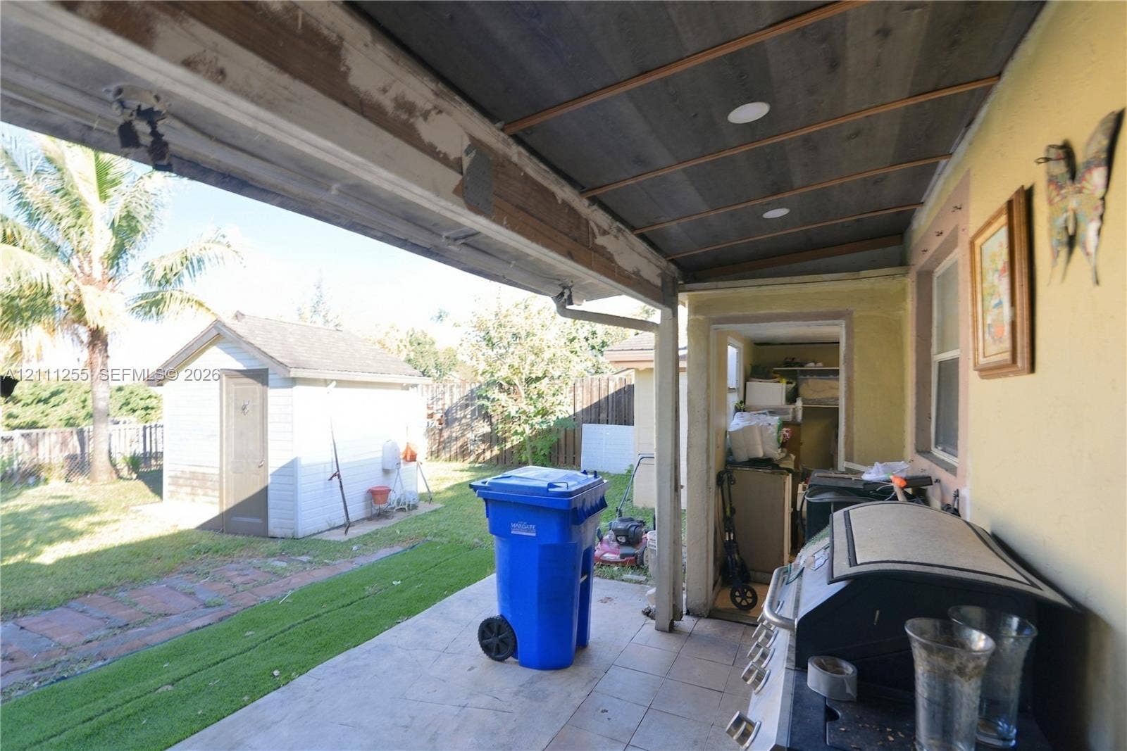Covered patio featuring a wood-plank ceiling with recessed lighting and concrete flooring, inclusive of a detached storage structure