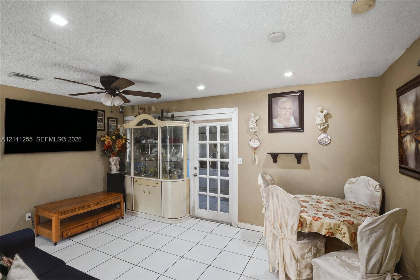 Interior space featuring neutral wall paint, white tile flooring, recessed ceiling lighting, a ceiling fan with integrated lighting, and a multi-pane glass door