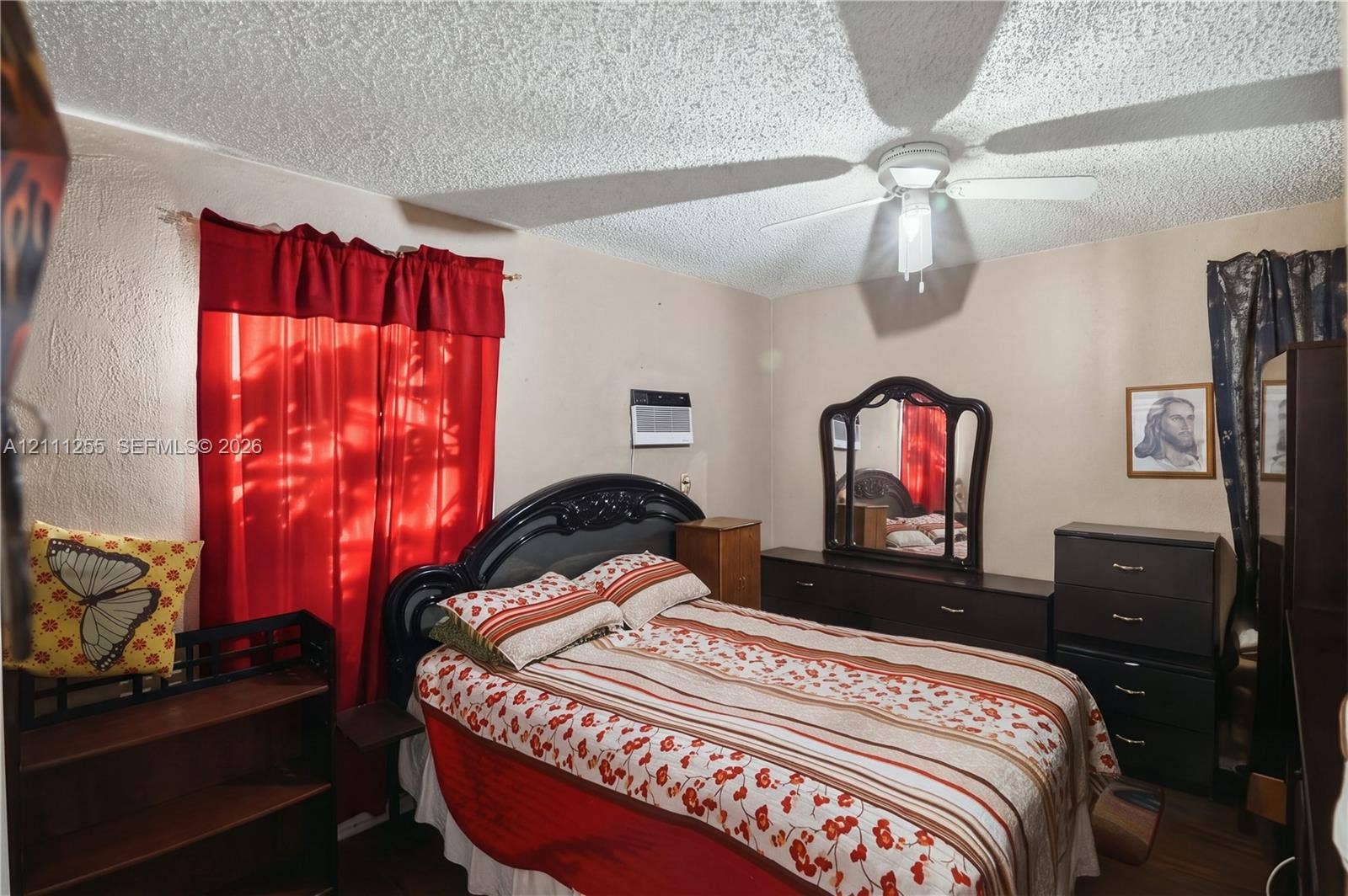 Textured ceiling with a central multi-blade ceiling fan and wall-mounted air conditioning unit
