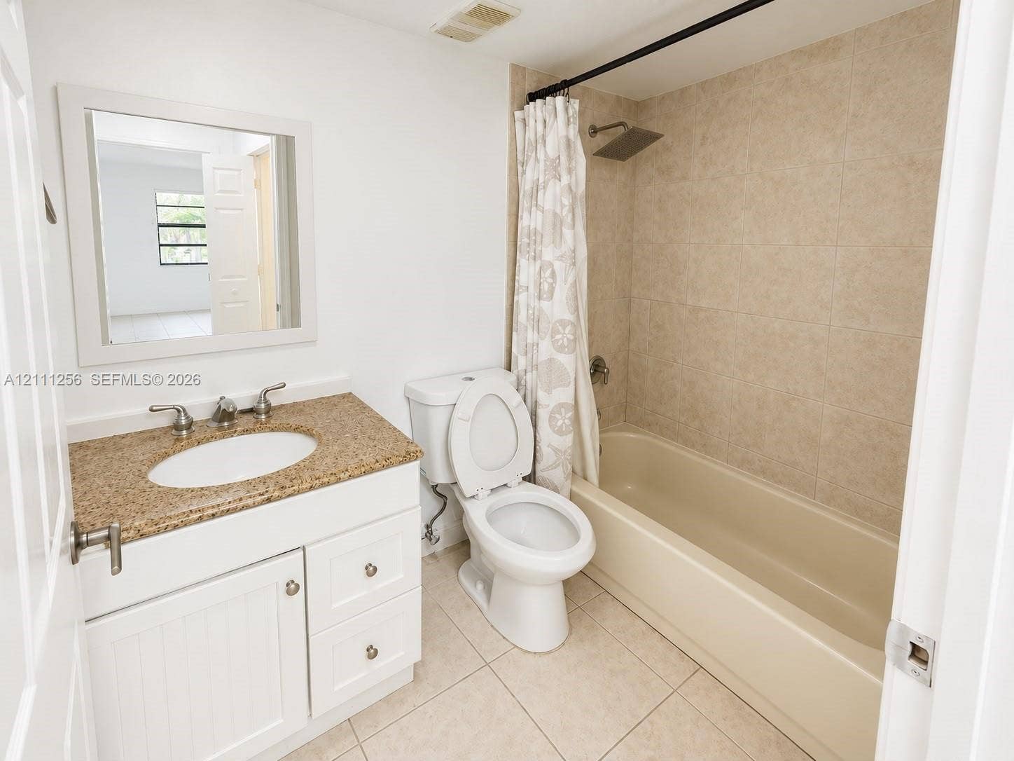 White vanity with speckled stone countertop, integrated sink, large wall-mounted mirror, ceramic tile shower surround, and square rainfall showerhead