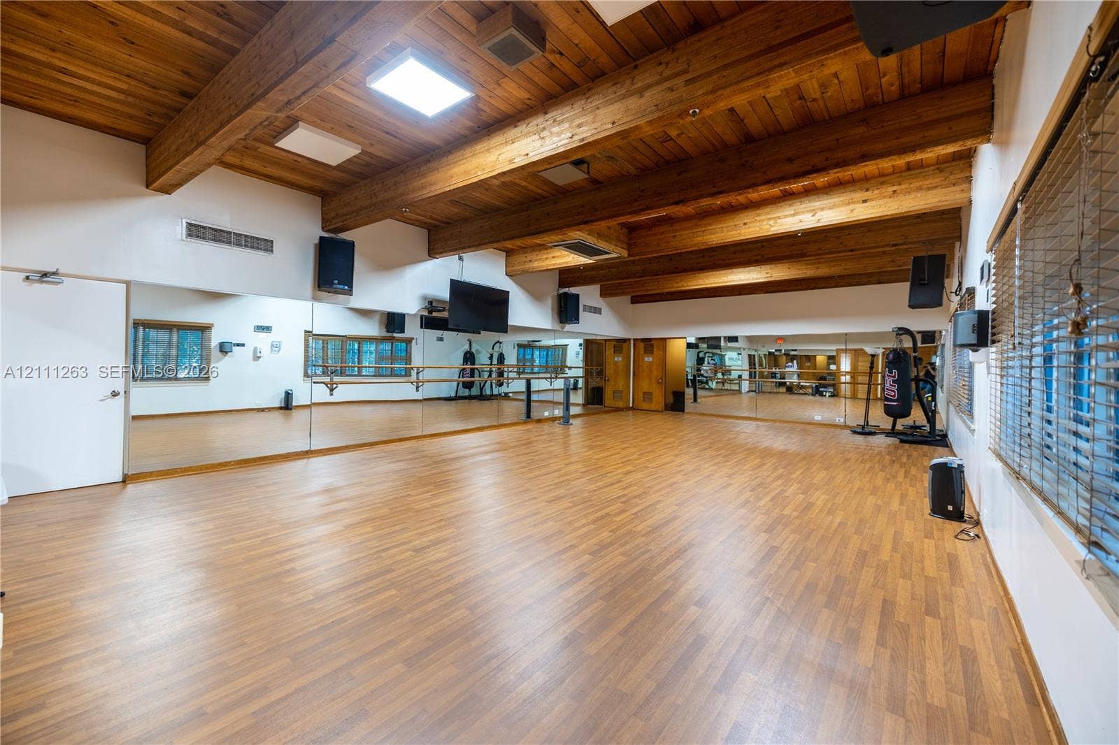 4000 Towerside Terrace, #604, Miami, FL 33138 Expansive room featuring vaulted wood-plank ceilings with exposed timber beams, wood-finish flooring, full-length wall mirrors, and a wall-mounted ballet barre