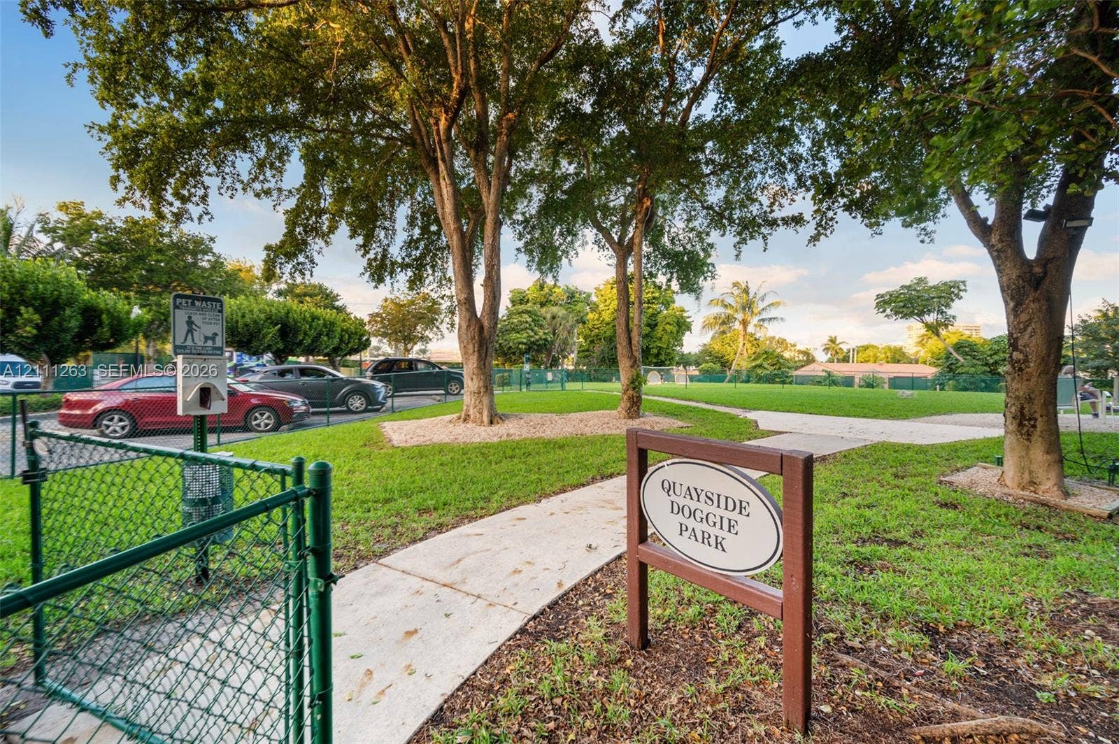 4000 Towerside Terrace, #604, Miami, FL 33138 Enclosed recreation area featuring green space, concrete pathways, mature trees, and chain-link fencing