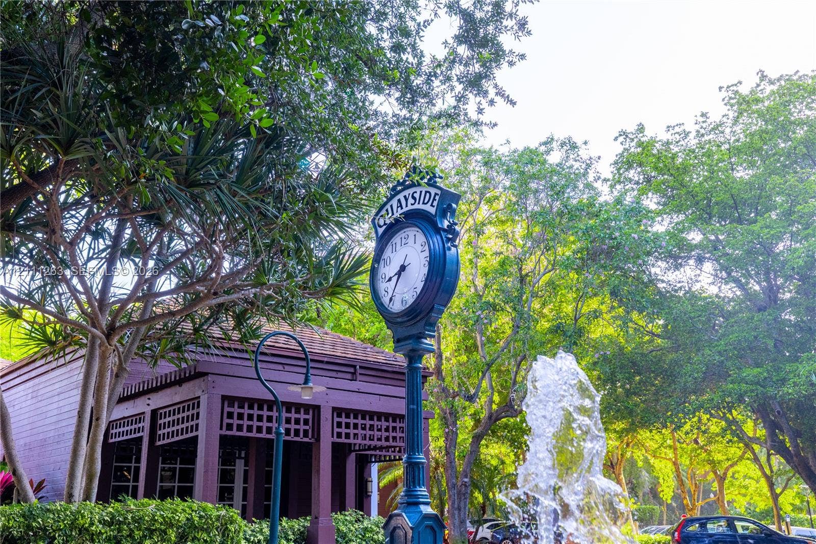 4000 Towerside Terrace, #604, Miami, FL 33138 Landscaped grounds featuring a water fountain, decorative clock post, mature trees, and a wooden structure with lattice detailing