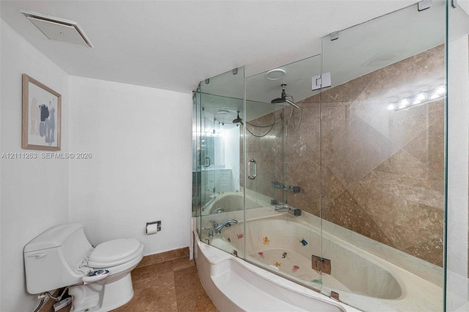 4000 Towerside Terrace, #604, Miami, FL 33138 Glass-enclosed soaking tub with stone tile surround, integrated shower fixture, and ceramic floor tile
