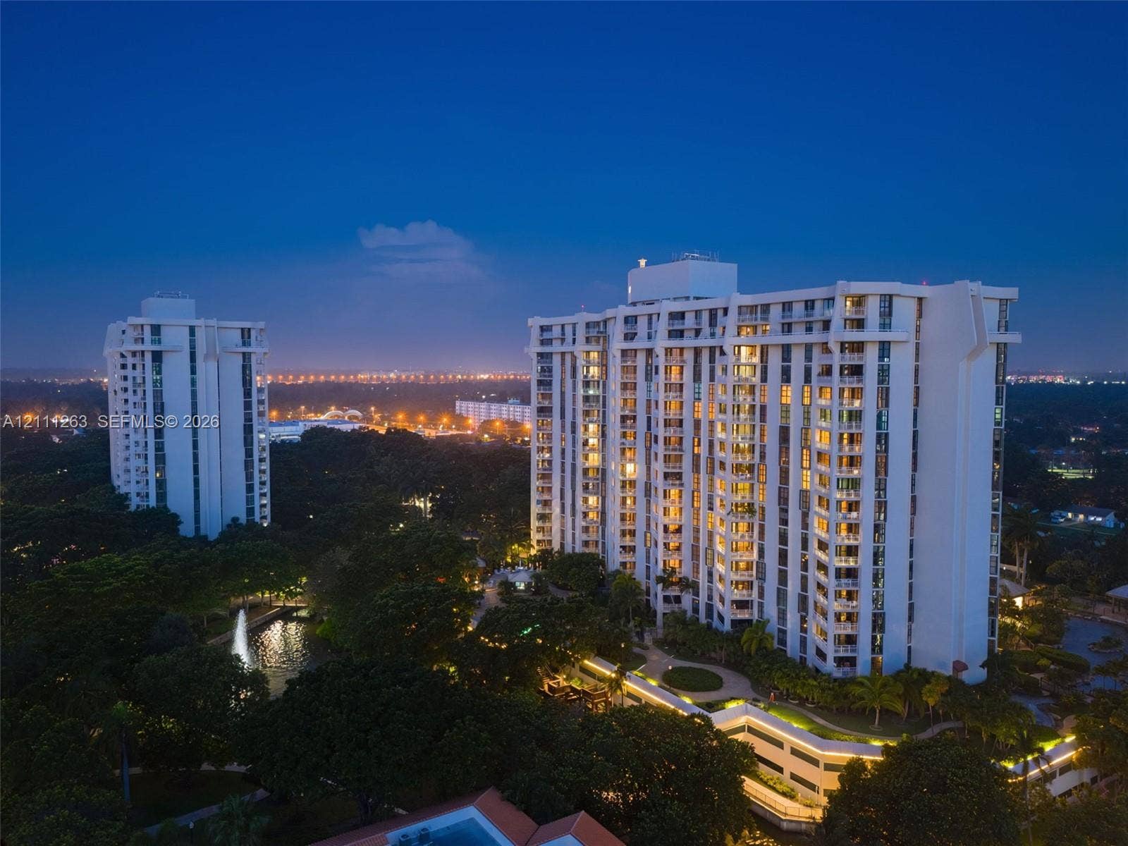 4000 Towerside Terrace, #604, Miami, FL 33138 High-rise residential architecture featuring private balconies, integrated building lighting, and surrounding landscaped grounds with a water feature