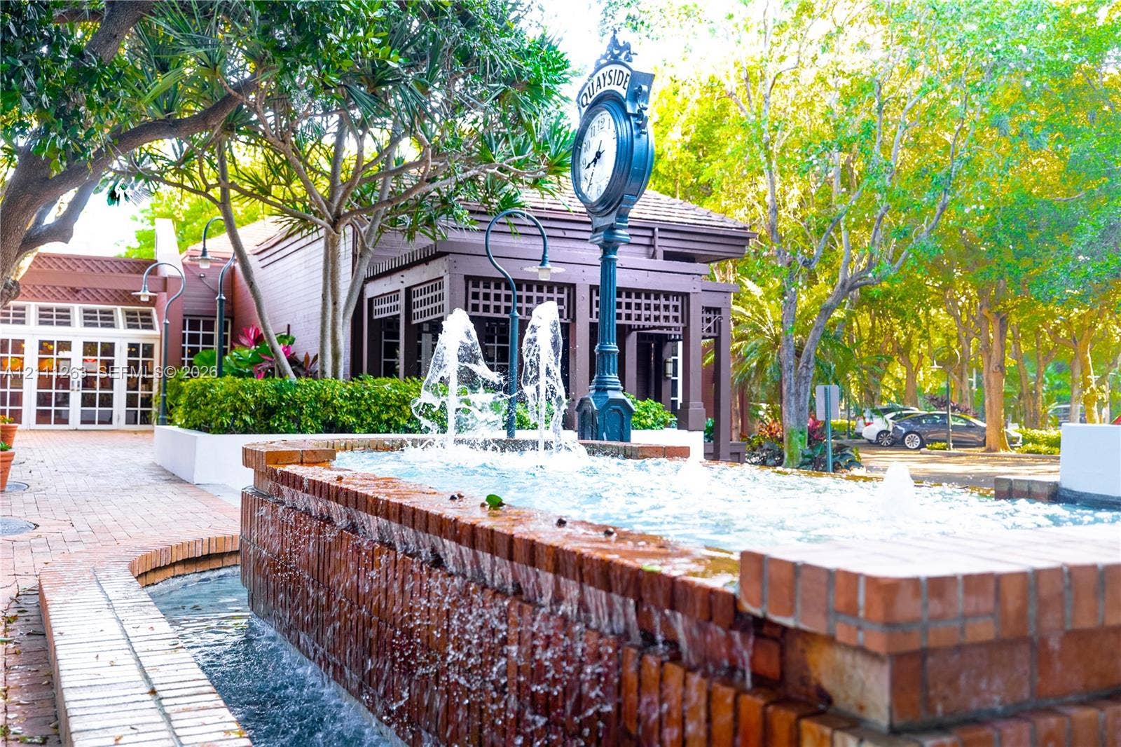 4000 Towerside Terrace, #604, Miami, FL 33138 Tiered brick fountain with integrated water jets, decorative street-style clock, brick-paved walkways, and established landscape foliage