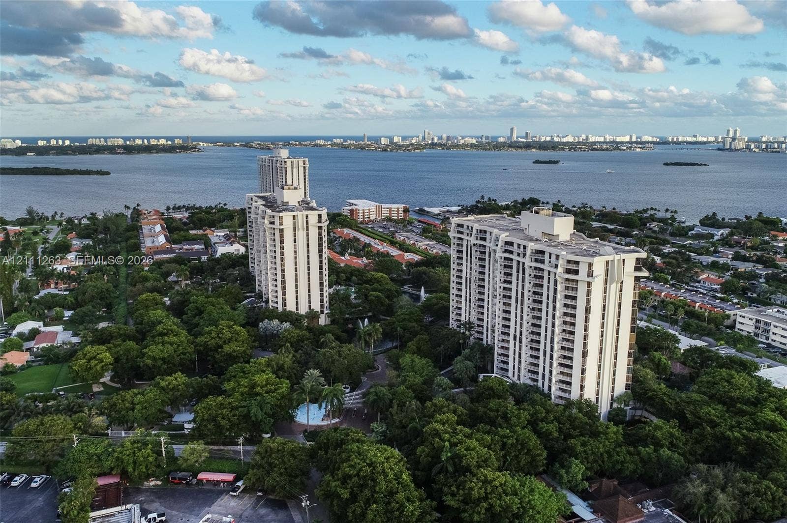 4000 Towerside Terrace, #604, Miami, FL 33138 Aerial perspective featuring two high-rise towers, mature tree canopy, water backdrop, and circular swimming pool