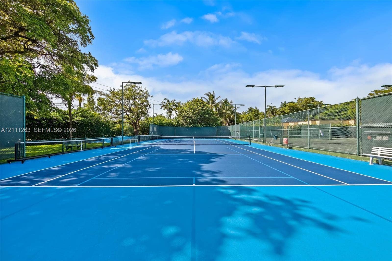 4000 Towerside Terrace, #604, Miami, FL 33138 Hard-surface tennis court featuring perimeter chain-link fencing, overhead pole lighting, and built-in bench seating