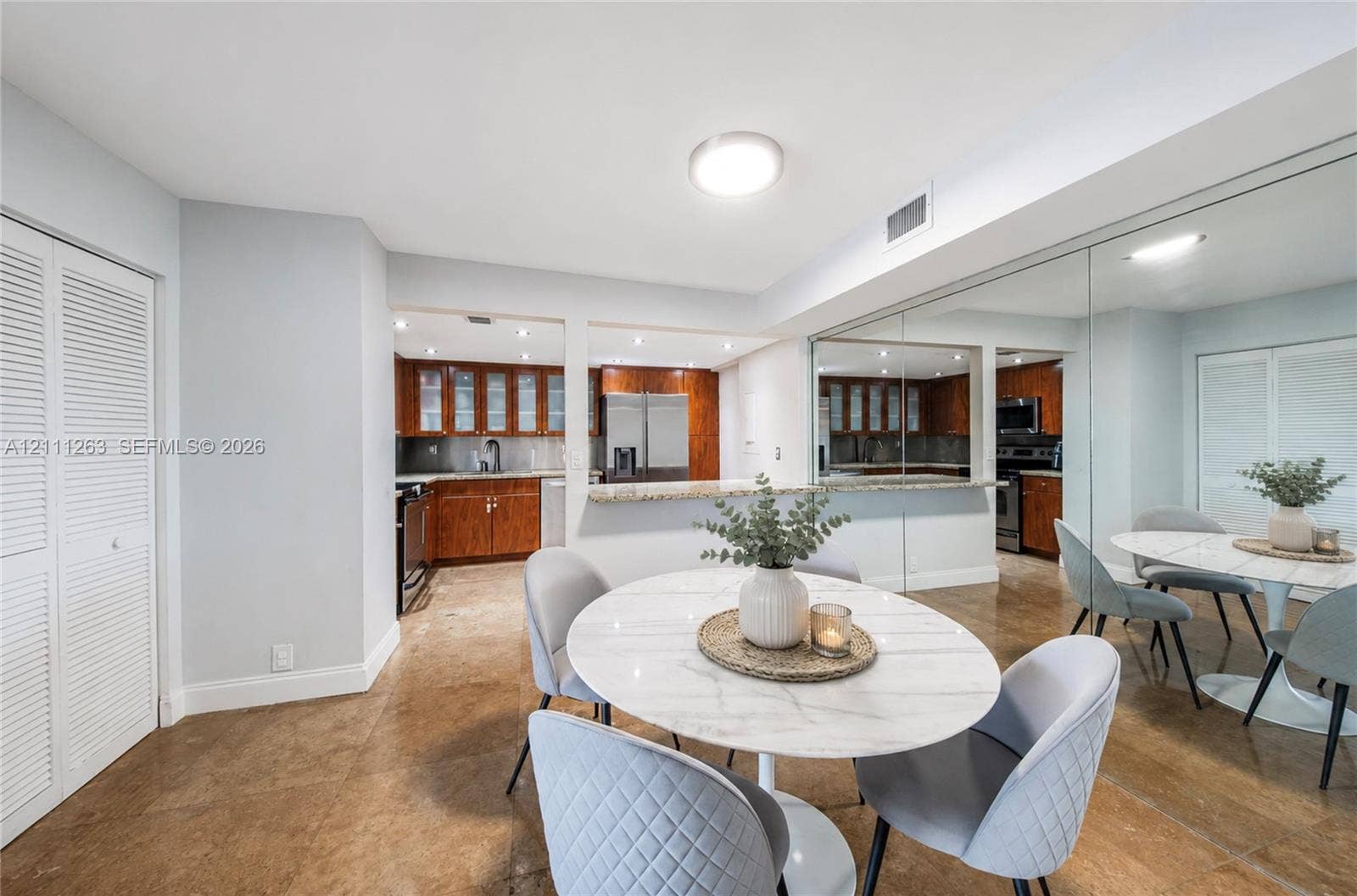 4000 Towerside Terrace, #604, Miami, FL 33138 Kitchen featuring wood cabinetry, stone countertops, a breakfast bar, and large wall-mounted mirrors