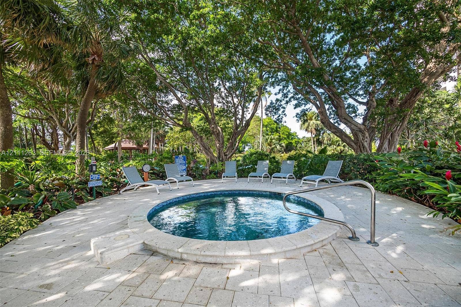 4000 Towerside Terrace, #604, Miami, FL 33138 Circular jetted spa with tile interior, stone-paver deck, stainless steel handrail, and mature surrounding landscaping