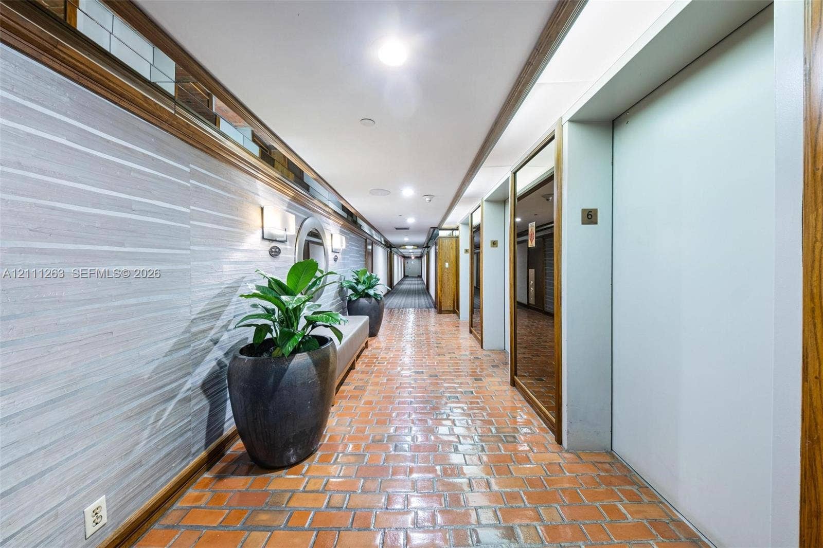 4000 Towerside Terrace, #604, Miami, FL 33138 Hallway featuring brick flooring, textured wall covering, wood-trim detailing, mirrored panels, and recessed ceiling lighting
