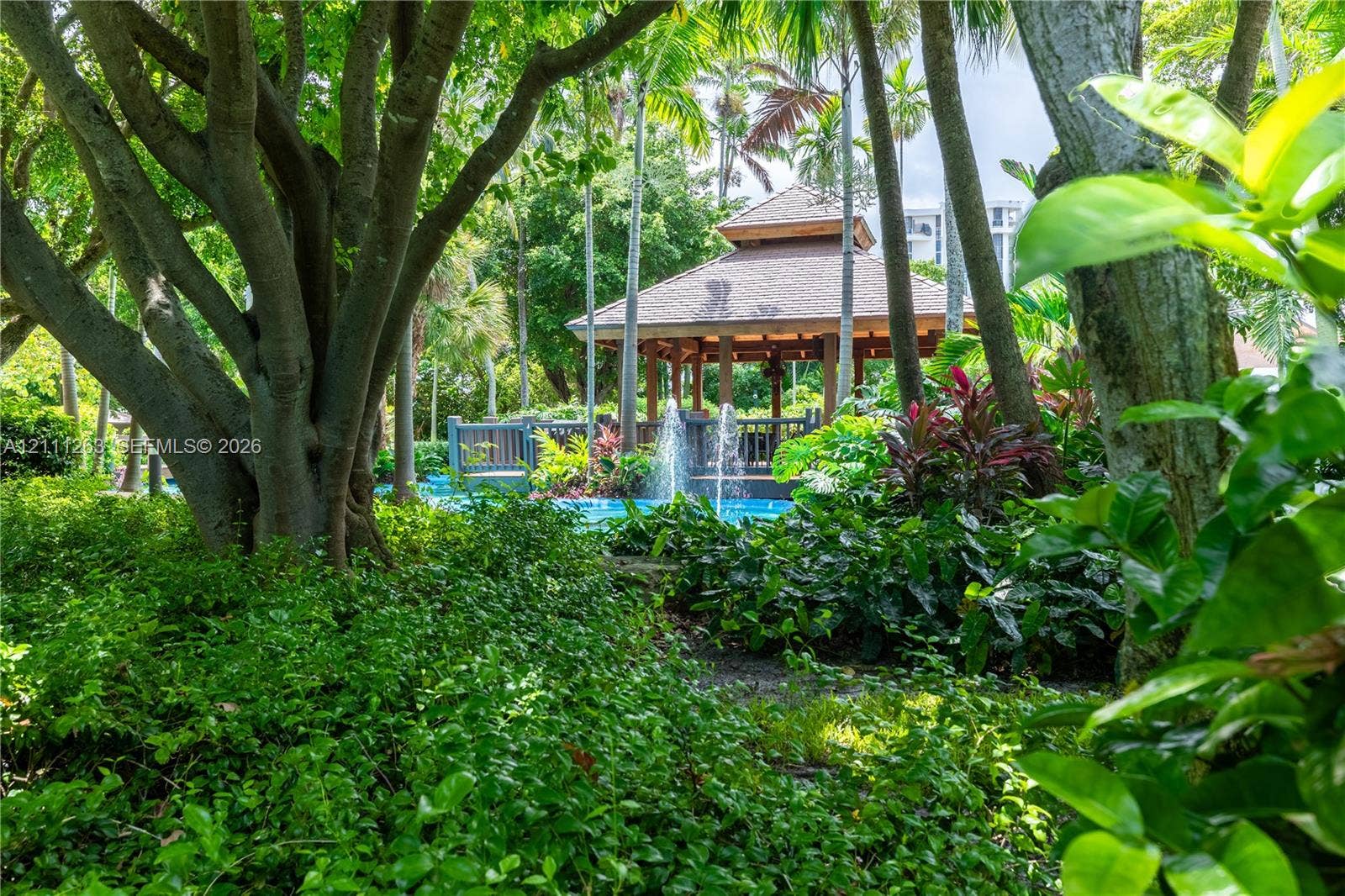 4000 Towerside Terrace, #604, Miami, FL 33138 Outdoor grounds featuring a wooden gazebo, water fountain, mature palm trees, and lush landscaping