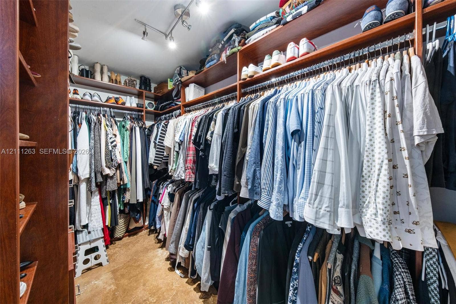 4000 Towerside Terrace, #604, Miami, FL 33138 Walk-in closet featuring extensive wall-to-wall wood-finish cabinetry, tiered hanging rods, multiple open storage shelves, and ceiling-mounted directional track lighting