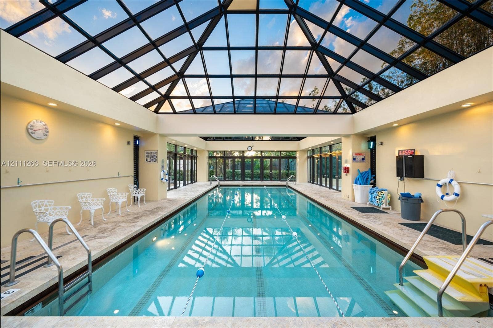 4000 Towerside Terrace, #604, Miami, FL 33138 Indoor swimming pool enclosure featuring a vaulted glass atrium roof, natural stone tile decking, and full-length glass paneled walls