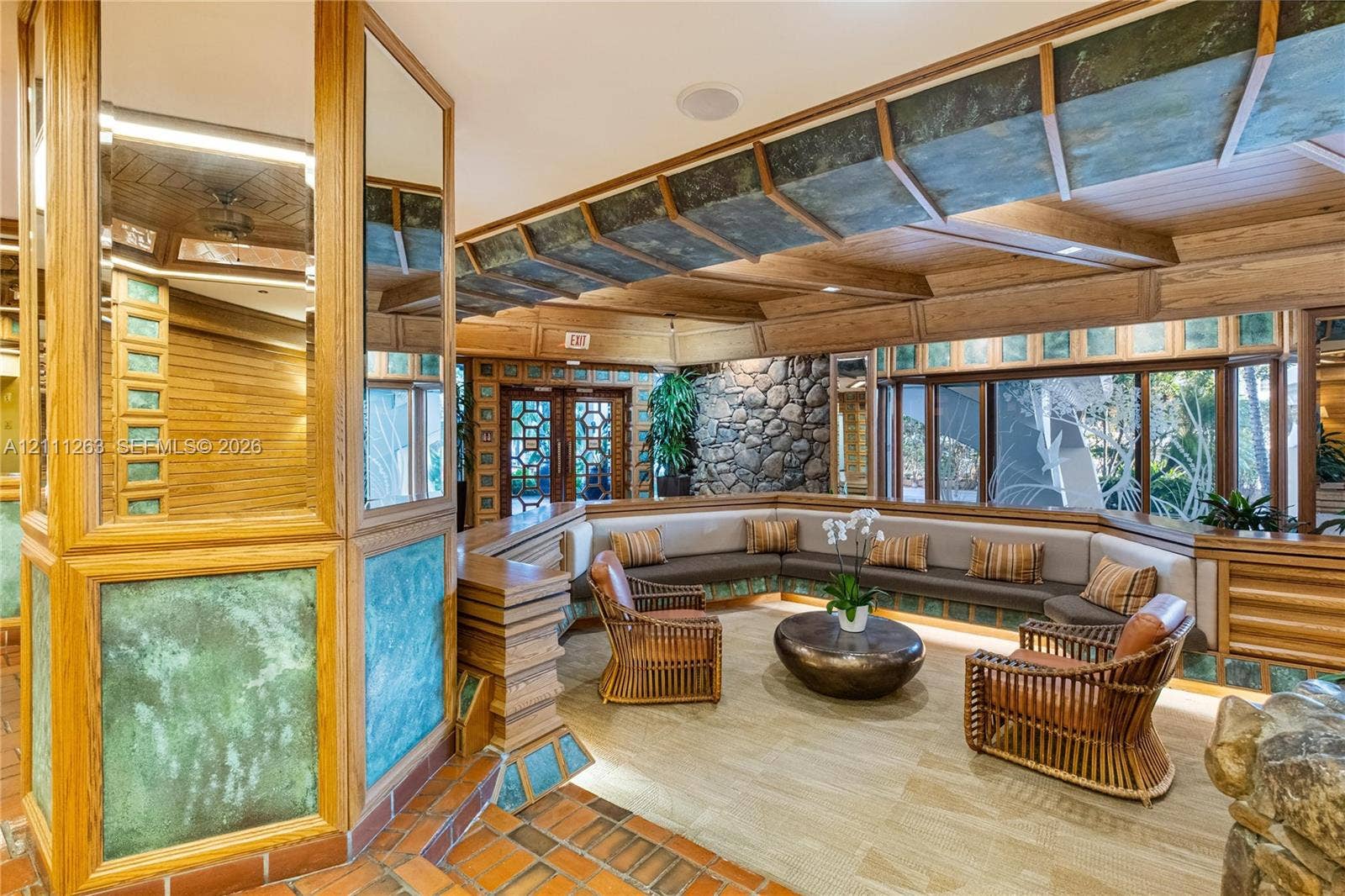 4000 Towerside Terrace, #604, Miami, FL 33138 Custom architectural interior featuring natural wood-finish beams, stacked stone accent walls, patterned glass paneling, terracotta-tone tile flooring, and integrated built-in seating