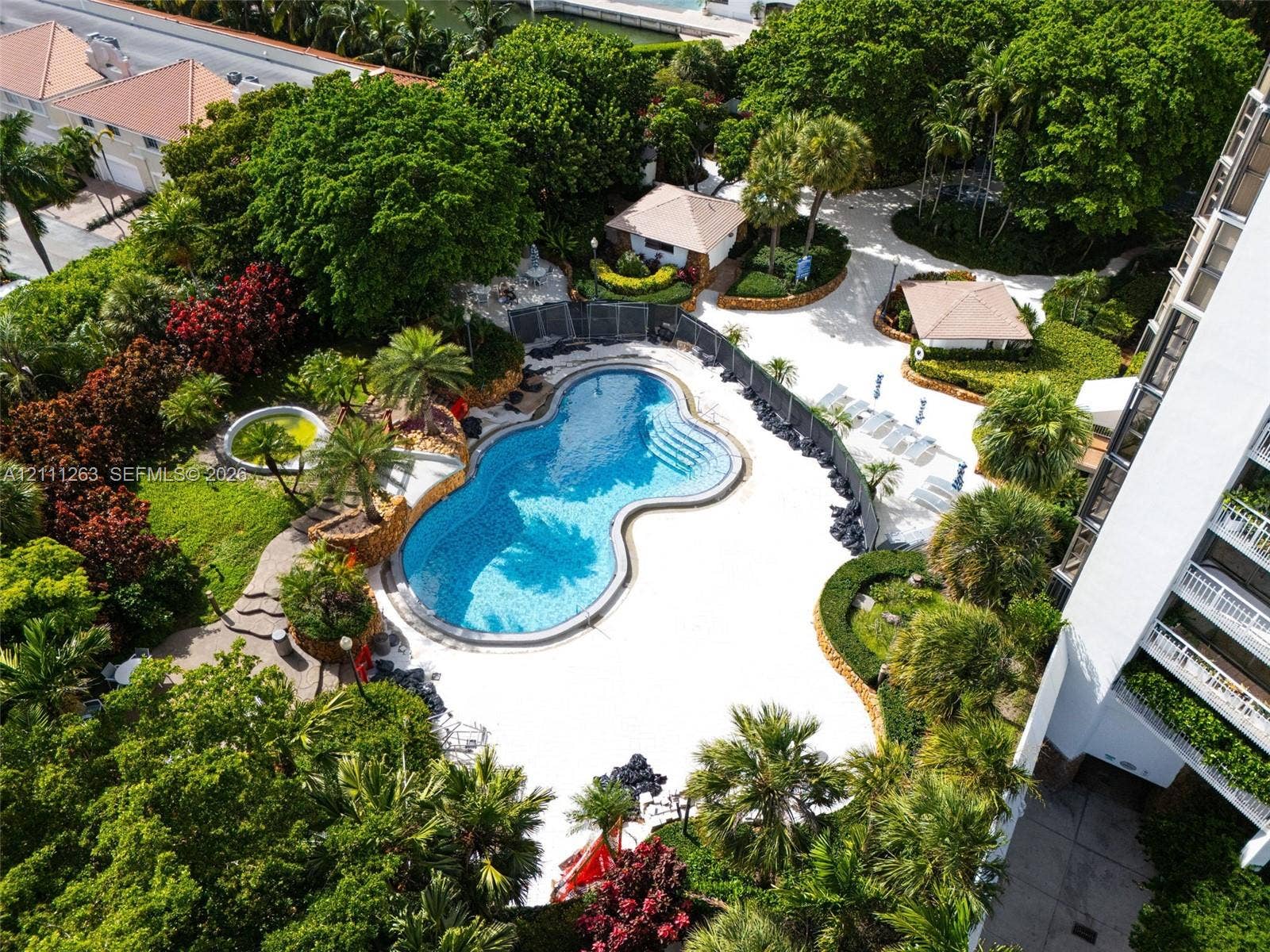 4000 Towerside Terrace, #604, Miami, FL 33138 Freeform swimming pool with stone-accented perimeter, expansive paved sundeck, mature tropical landscaping, and dedicated covered structures