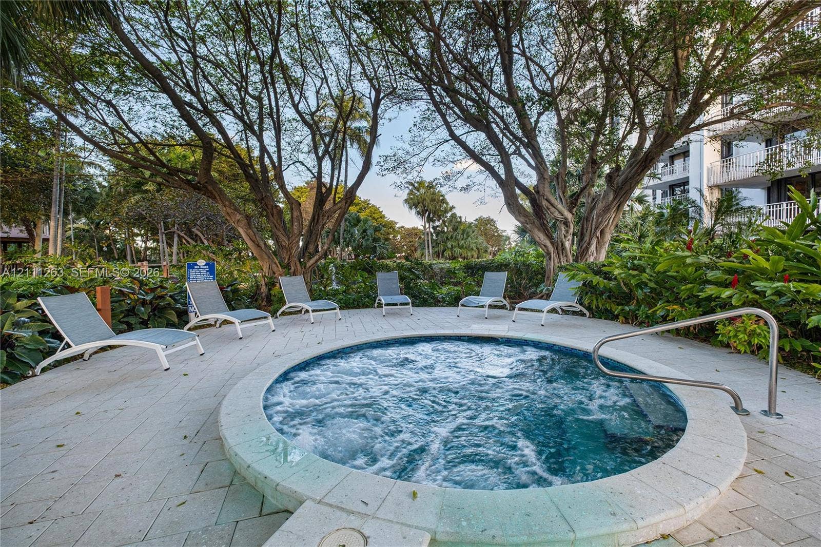 4000 Towerside Terrace, #604, Miami, FL 33138 In-ground circular spa featuring a light-colored paver surround, integrated metal handrail, and mature surrounding landscaping