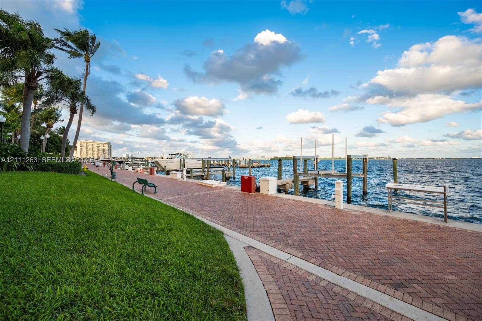 4000 Towerside Terrace, #604, Miami, FL 33138 Waterfront promenade featuring a herringbone-patterned paver path, manicured lawn, and multiple deep-water boat slips