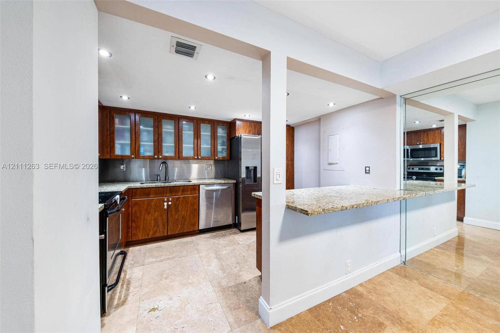 4000 Towerside Terrace, #604, Miami, FL 33138 Kitchen featuring stone-finish countertops, stainless steel appliances, upper cabinetry with glass-panel doors, stone-tile flooring, and a stone-topped breakfast bar