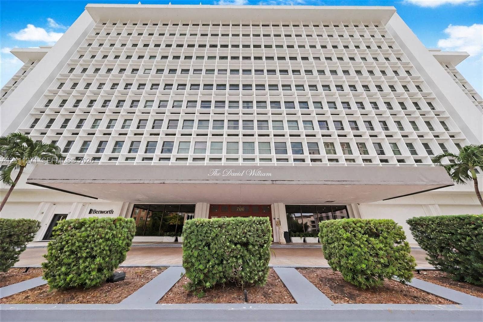 Mid-century modern high-rise exterior featuring a distinctive concrete grid faade, cantilevered entrance canopy, and manicured landscaping