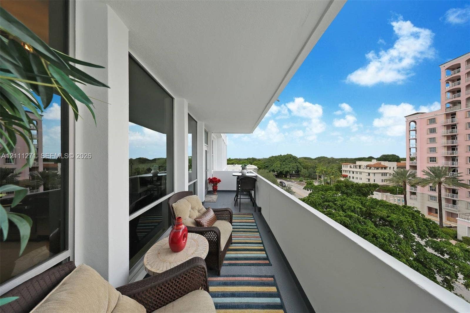 Covered private balcony featuring floor-to-ceiling glass paneling and a solid partition railing