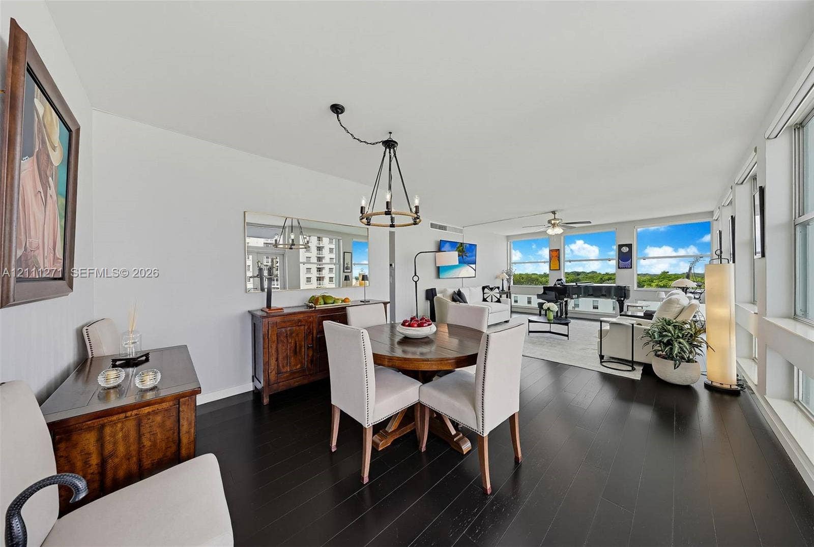 Open-concept living space featuring wood-finish flooring, a wall-mounted mirror, a multi-arm chandelier, and expansive windows